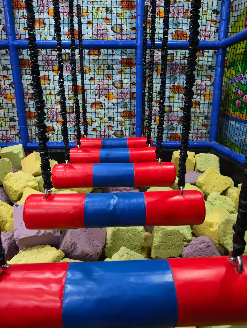 Padded hanging-step obstacle over a foam pit at Rainbow Kids Zone