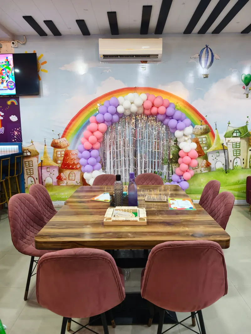 Rainbow-themed birthday lounge with a balloon arch at Rainbow Kids Zone